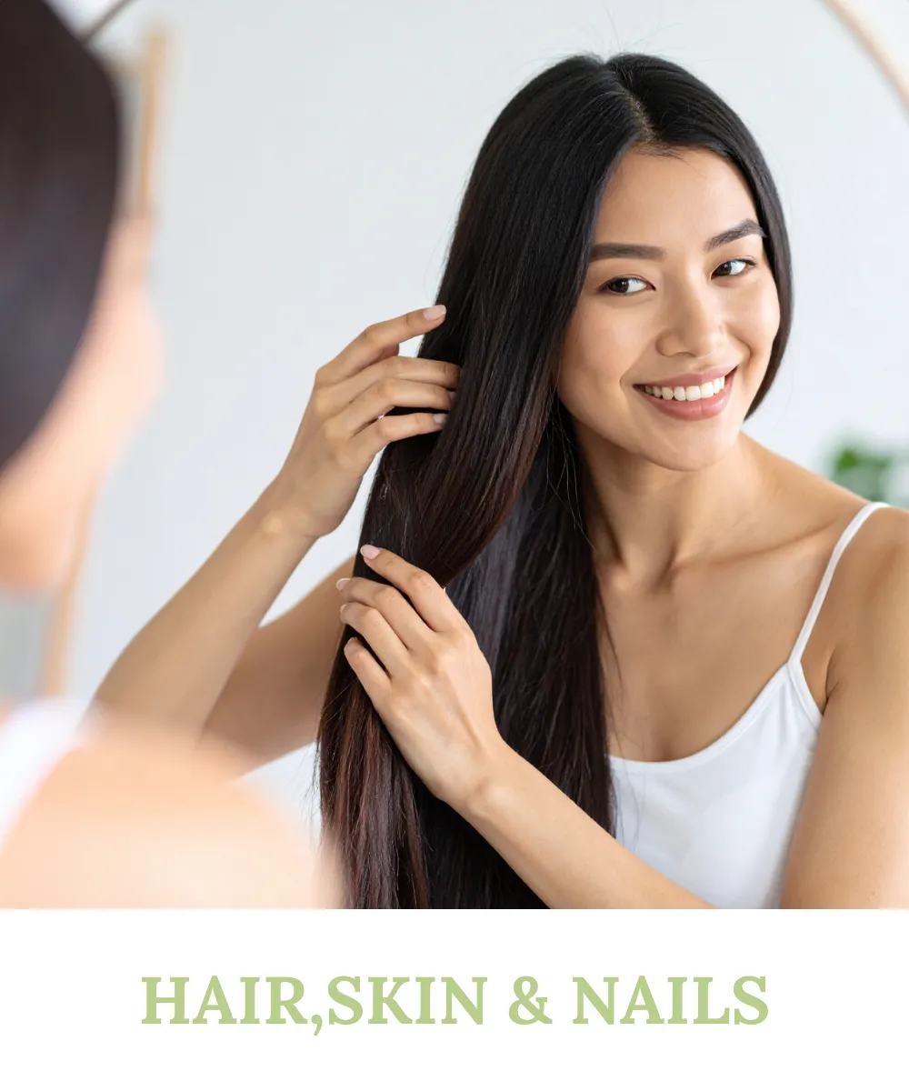A beautiful woman smiling while looking at her reflection and touching her long, healthy hair, representing Sihat365 for radiant hair, skin, and nails.